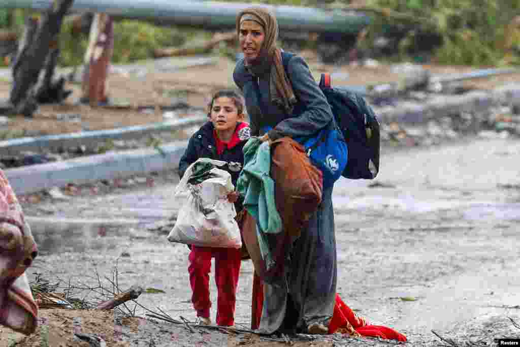 A barefooted Palestinian woman fleeing north Gaza with her daughter moves southward during rainfall amid a temporary truce between Israel and Hamas, near Gaza City.
