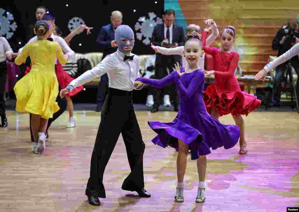 Roman, 8, wounded by Russian missile strike on the central Ukrainian city of Vinnytsia last year, performs at a ballroom dance competition, with his face covered by a burn mask after a year of skin grafts and over 30 surgeries, in Lviv, Ukraine.