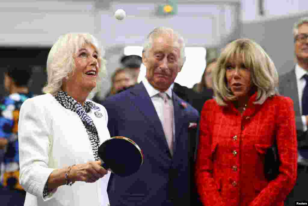 Britain's Queen Camilla plays table tennis next to Britain's King Charles, Brigitte Macron, wife of French President Emmanuel Macron as they meet local youth sports associations in Saint-Denis near Paris.