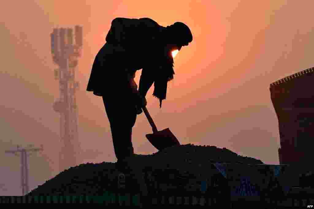 A laborer is silhouetted against the rising sun amid smoggy conditions in Lahore, Pakistan.