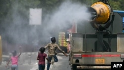 Anak-anak tampak berlari di belakang truk yang menyemprotkan air di sepanjang jalanan New Delhi, India, pada 28 Mei 2024. (Foto: AFP/Arun Sankar)