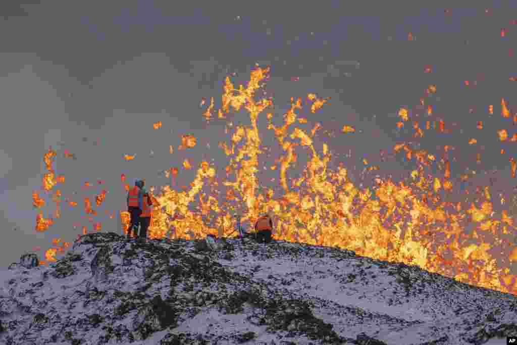 Scientist of the University of Iceland take measurements and samples standing on the ridge in front of the active part of the eruptive fissure of an active volcano in Grindavik on Iceland's Reykjanes Peninsula, Dec. 19, 2023.