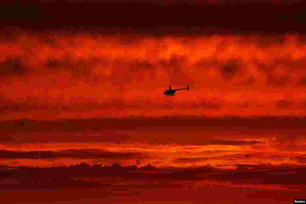 A helicopter travels south along the coast after sunset over the ocean as hurricane Hilary approaches Del Mar, California, Aug. 19, 2023.