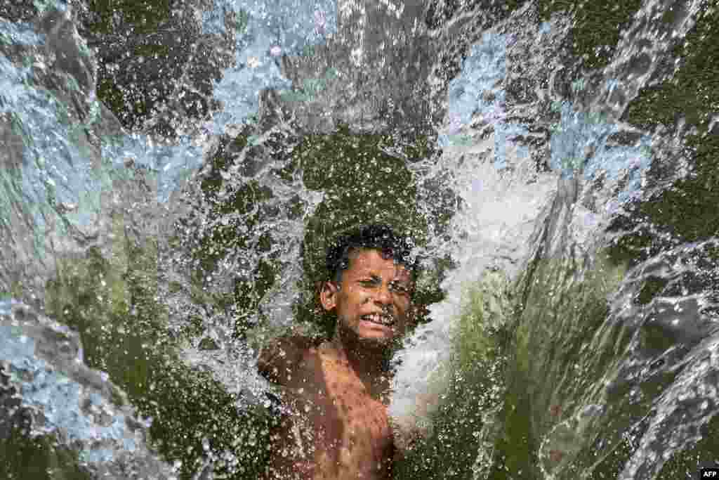 A child playfully takes a dip in a lake to get respite from the heat on a summer afternoon in Dhaka, Bangladesh.