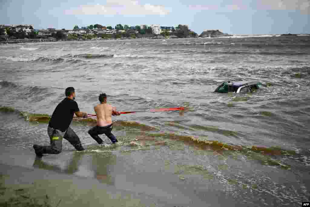 People pull a car submerged in the sea at Arapia camping site near Tsarevo along the Bulgarian Black sea coast. Heavy rain and thunderstorms since late Sept. 4 caused rivers to overflow, damaging bridges and causing more than 100 seaside holidaymakers and locals to be evacuated to safer grounds. 