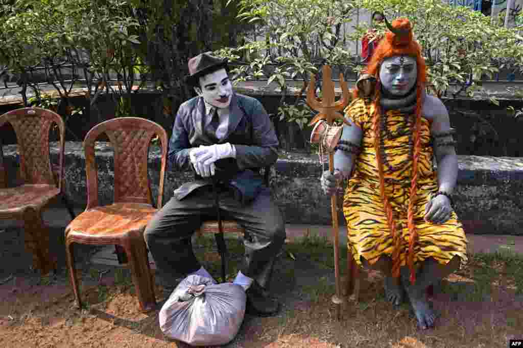 Artists dressed as Charlie Chaplin, left, and Hindu lord Shiva wait to perform during a program organized to promote and create awareness about the traditional folk art form of polymorphic Bahuroopiya, in Kolkata, India.