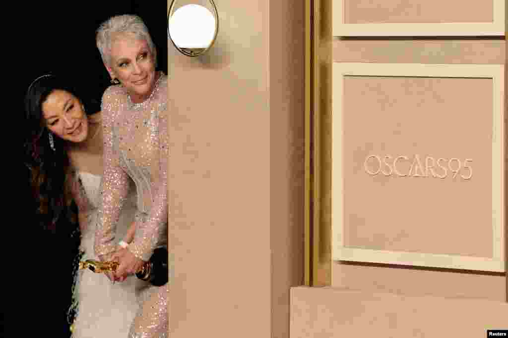Oscar winners Jamie Lee Curtis and Michelle Yeoh watch backstage as Brendan Fraser (unseen) poses with his Oscar in the Oscars photo room at the 95th Academy Awards in Hollywood, Los Angeles, California, March 12, 2023.