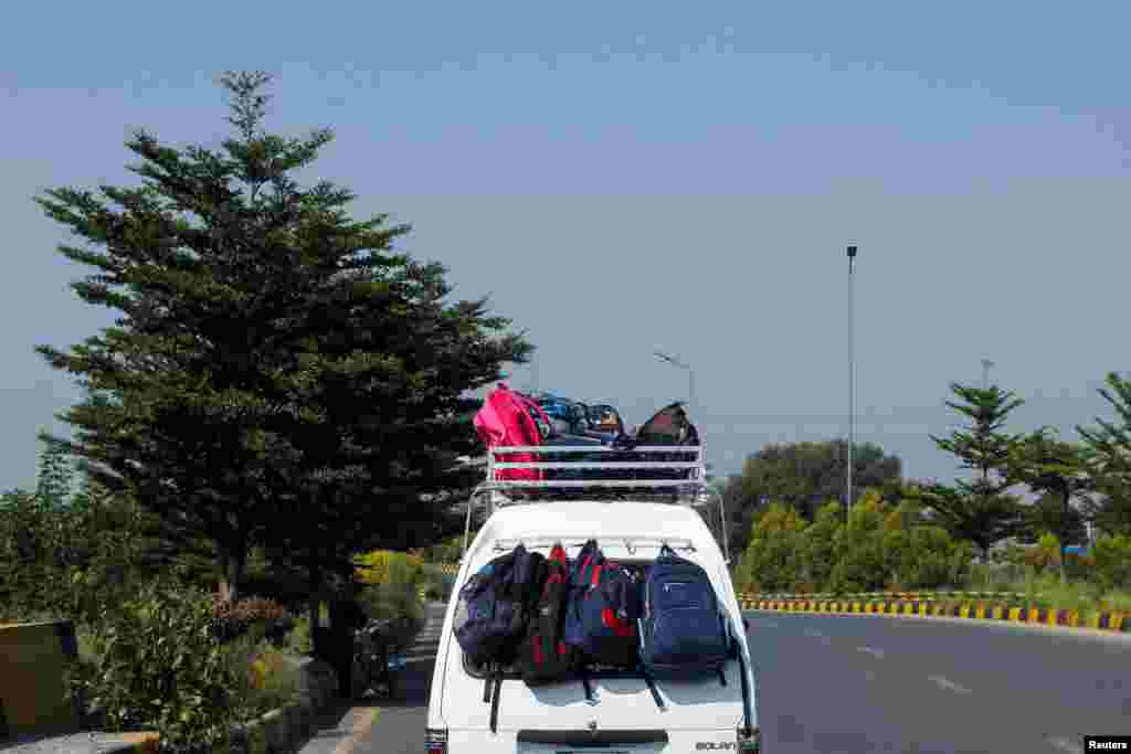 Bagpacks belonging to students hang from the back of a school van, on a road in Rawalpindi, Pakistan.