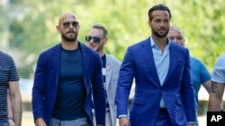 Andrew Tate, left, and his brother Tristan, arrive flanked by bodyguards, at the Bucharest Tribunal in Bucharest, Romania, July 17, 2023. 