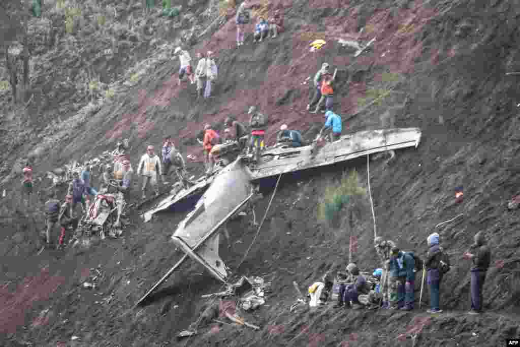 People inspect the wreckage of an Indonesia's Air Force EMB-314 Super Tucano plane that crashed in Pasuruan, East Java. Four people, including two pilots, were killed in Indonesia on November 16 when two military aircraft crashed into a mountainside during training, an air force spokesperson said. 