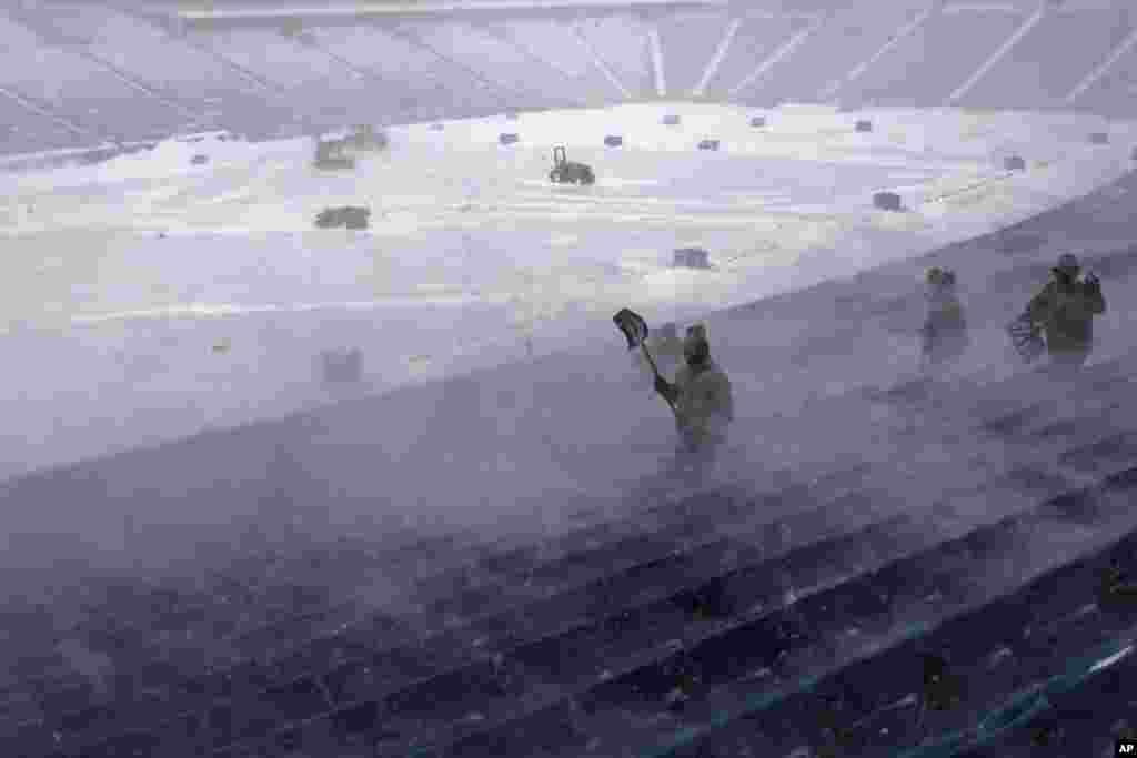 Workers remove snow from Highmark Stadium in Orchard Park, New York. A potentially dangerous snowstorm that hit the Buffalo region led the NFL to push back the Bills wild-card playoff game against the Pittsburgh Steelers from Sunday to Monday. 
