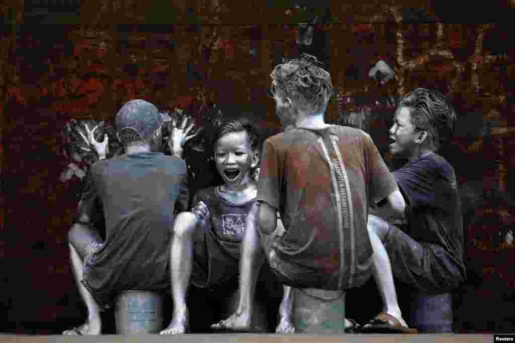 Youths, who covered themselves in silver paint to become 'manusia silver' (silvermen) to make a living, laugh as they ride on the back of a truck in Jakarta, Indonesia.