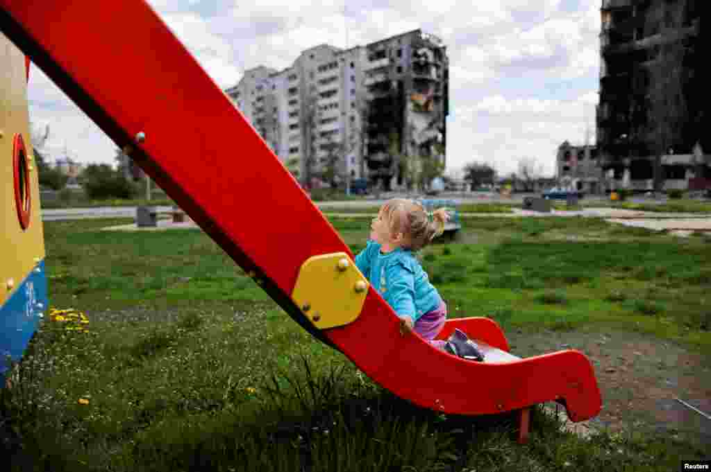 Nina Stefuryak, 2, plays at the playground in front of a building destroyed by shelling in Borodianka, Kyiv region, Ukraine, amid the Russian invasion of Ukraine, May 2, 2022.