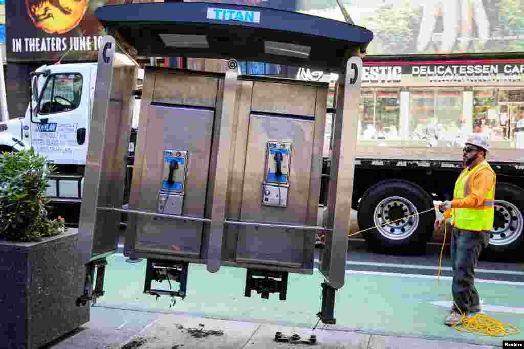 A worker removes the last public payphone near Times Square in New York City, May 23, 2022.