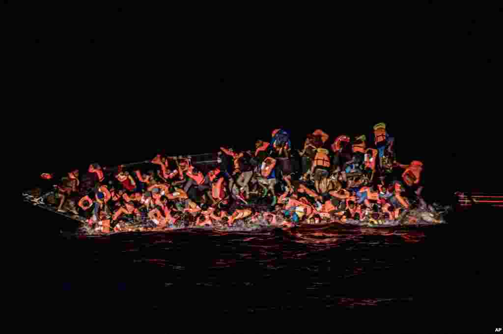 Dozens of migrants fall in the water while they struggle to cling to the side of an upturning boat off the waters of Tunisia.