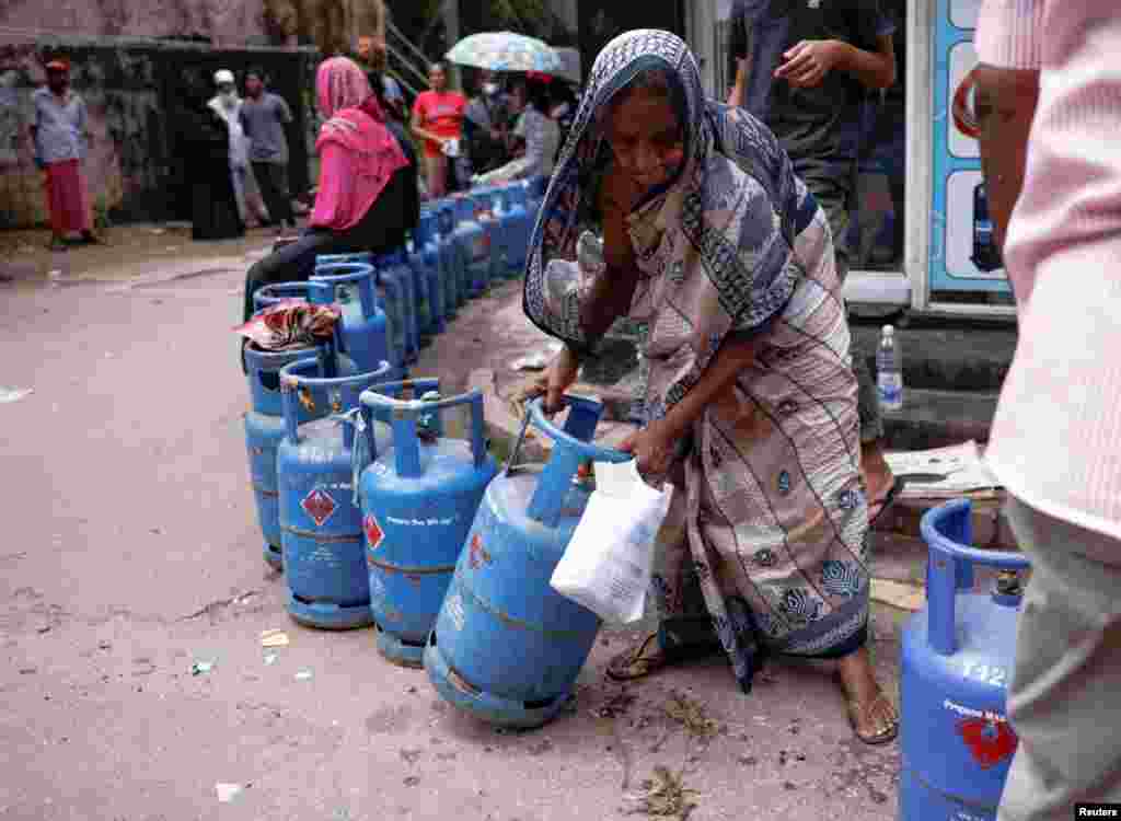 A woman moves a gas tank as she waits in line near a distributor amid the country's economic crisis, in Colombo, Sri Lanka.