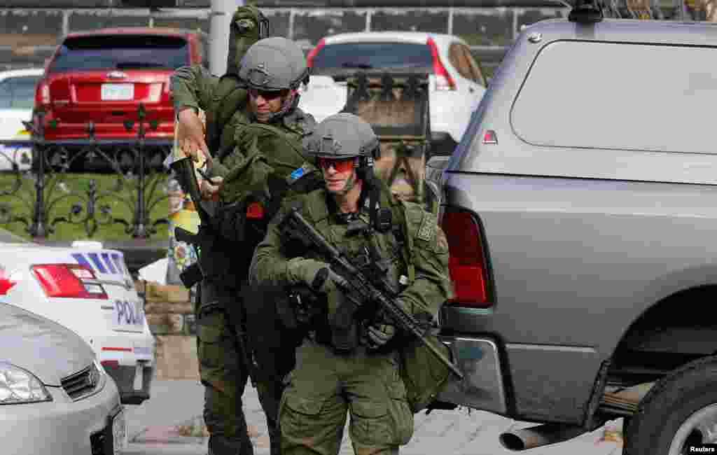 Armed RCMP officers approach Parliament Hilll following a shooting incident in Ottawa. A Canadian soldier was shot at the Canadian War Memorial and a shooter was seen running towards the nearby parliament buildings, where more shots were fired, according to media and eyewitness reports.