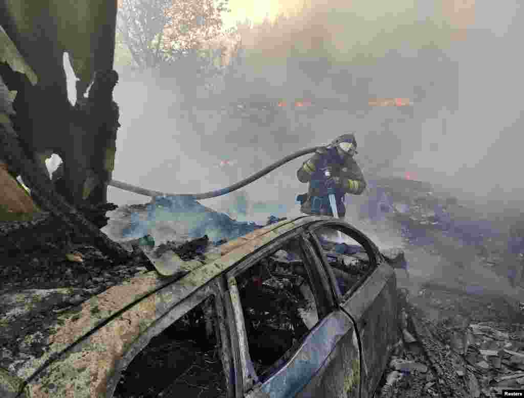 A firefighter extinguishes a fire at a warehouse following recent shelling in Donetsk, Ukraine.