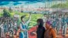 FILE - A couple wearing face masks walk past a painting to mark the country's Youth Day holiday in Soweto, South Africa, June 16, 2020. 