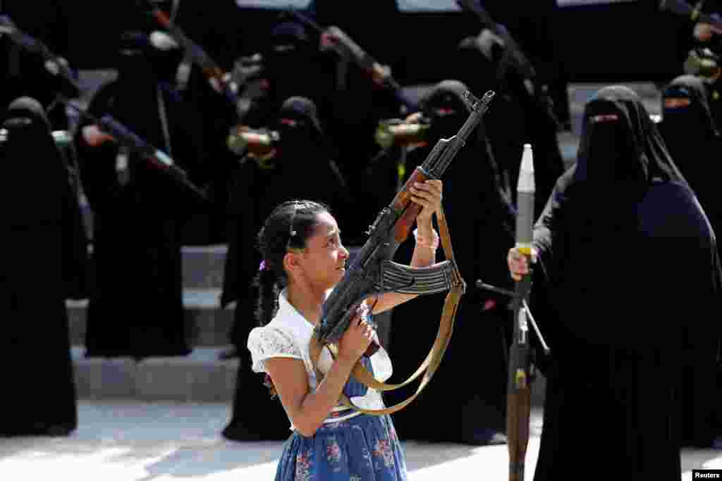 Seorang anak perempuan memegang senjata dalam sebuah aksi unjuk rasa para perempuan Yaman pendukung pemberontak Houthi di ibukota Sana'a.