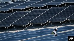 FILE - A worker installs solar panels on a roof at Van Nuys Airport in Los Angeles, California, Aug. 8, 2019.