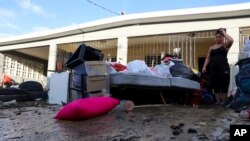 Žena posmatra svoje stvari koje je oštetila poplava izazvana uraganom Fiona, u Toa Baji, Portriko, 20. septembra 2022.
