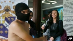 Student receives rose from protester during naked run to condemn last week's burial of late dictator Ferdinand Marcos at the Heroes' Cemetery, Quezon City, Philippines, Nov. 25, 2016.