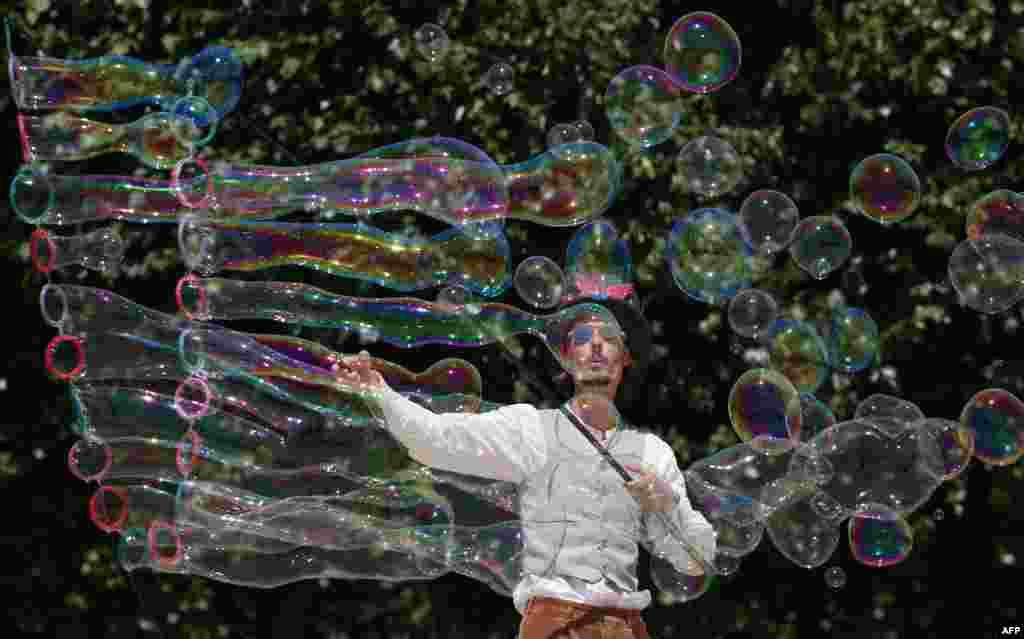 A street artist blows bubbles during a performance in Paris, as a heat wave sweeps across much of France and Europe.