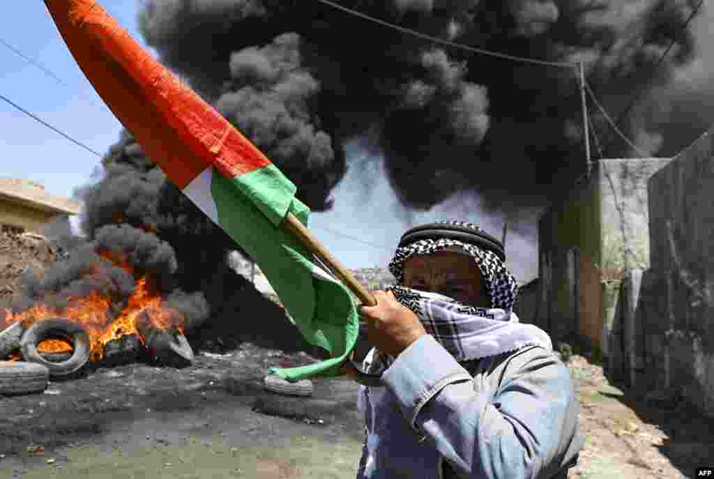 An elderly Palestinian man holds a national flag during clashes with Israeli forces following a demonstration against the expropriation of Palestinian land by Israel, in the village of Kfar Qaddum near the Jewish settlement of Kedumim in the occupied West