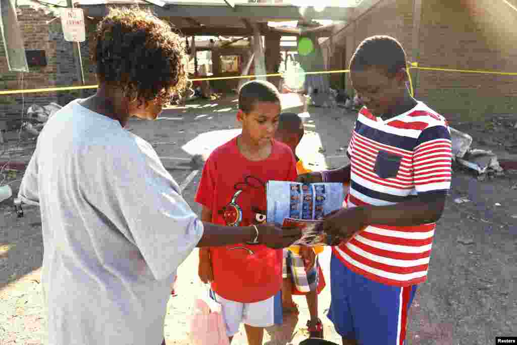 Jordan Humphrey, a 6th grader at tornado-damaged Briarwood elementary school, shows his mother Mary and his brother Jacob his soggy yearbook after his backpack was retrieved for him by a firefighter in Oklahoma City, Oklahoma, May 22, 2013.