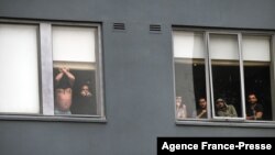 FILE - Asylum seekers gesture to protesters holding a pro-refugee rights rally from their hotel room where they have been detained in Melbourne on June 13, 2020.