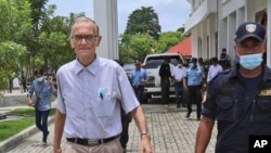 FILE - A police officer escorts Richard Daschbach, left, a former US missionary from Pennsylvania, upon his arrival for a trial at a courthouse in Oecusse, East Timor, Feb. 23, 2021.
