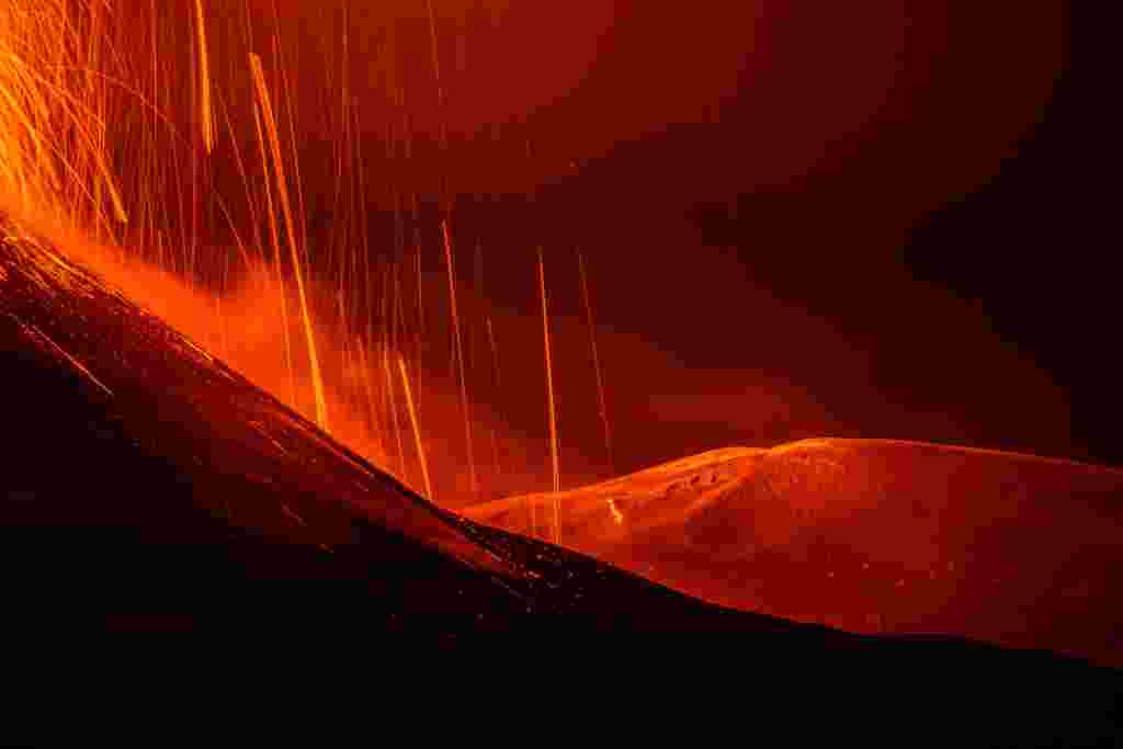 Streams of red hot lava flow as Mount Etna, Europe's most active volcano, erupts, as seen from Sant'Alfio, Italy.