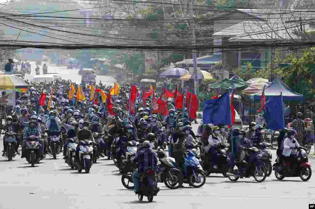 Protesters carry flags as they drive their motorcycles during an anti-coup protest in Mandalay, Myanmar.