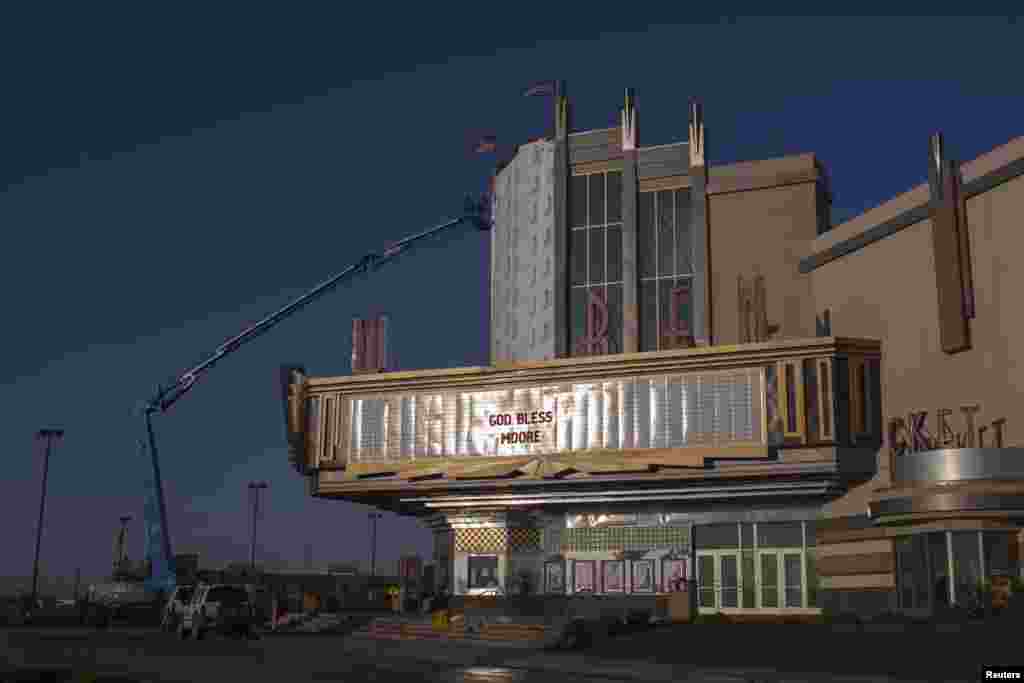 A sign reads "God Bless Moore" as workers make repairs to the Warren theater in Moore, Oklahoma, which was left devastated by a tornado, May 22, 2013.