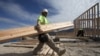 Construction worker Miguel Fonseca carries lumber as he works on a house frame for a new home, Nov. 16, 2012, in Chula Vista, Calif.