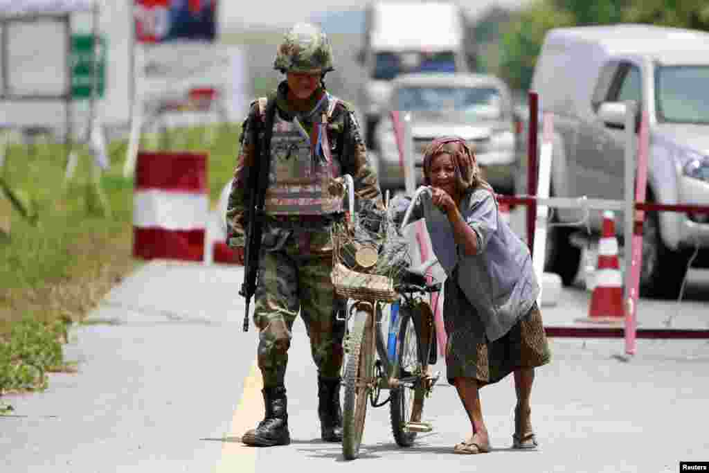Seorang perempuan mendorong sepedanya melalui sebuah pos pemeriksaan yang dijaga oleh pasukan keamanan Thailand di provinsi Yala, di Thailand selatan yang bergolak.