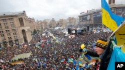A teenager waves a national flag over a crowd of Pro-European Union activists gathered during a rally in the Independence Square in Kyiv, Ukraine, Dec. 8, 2013.