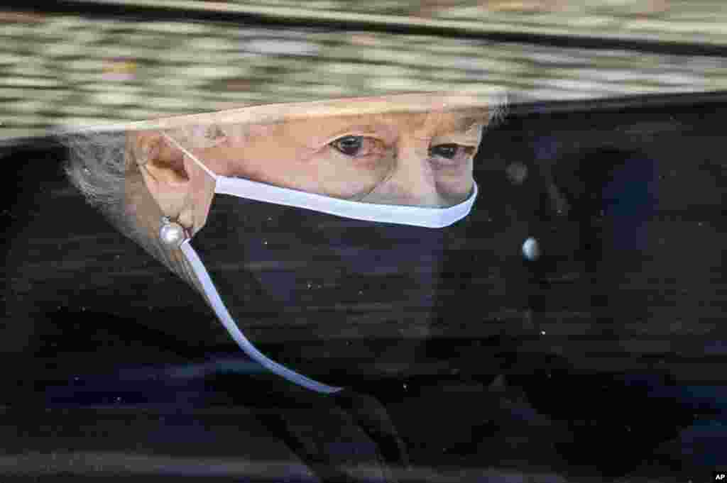 Britain's Queen Elizabeth II follows the coffin of her late husband Prince Philip, in a car as it makes it's way past the Round Tower during his funeral inside Windsor Castle in Windsor, England, April 17, 2021.
