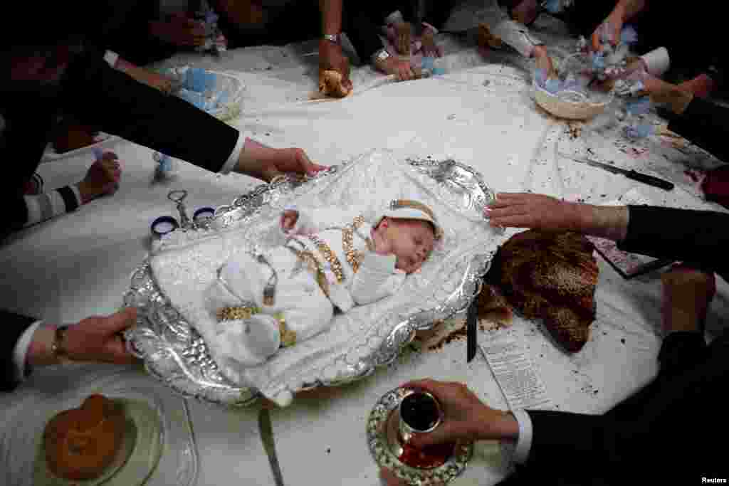 The great-grandson of the spiritual leader of the ultra-Orthodox Jewish Hassidic Lelover dynasty lies on a table during a religious ceremony, called "Pidyon Ha'ben", or the "redemption of the first-born son", originating from the biblical story of Moses on Mount Sinai, whereby the father of the baby makes a symbolic offering, including jewellery and sweets, to a Kohen or Jewish priest, in Jerusalem's neighbourhood of Mea Shearim.