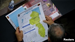  Un miembro de la Asamblea Nacional sostiene un mapa que muestra la disputada región del Esequibo como parte de Venezuela, mientras las tensiones entre Caracas y Guyana han aumentado en las últimas semanas, el 6 de diciembre 2023. 