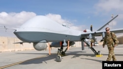 Perwira Angkatan Udara AS melintas di depan drone MQ-9 Reaper, salah satu skuadron yang tiba untuk meningkatkan pertempuran melawan Taliban, di pangkalan udara Kandahar, Afghanistan 23 Januari 2018. (Foto: Reuters/Omar Sobhani)