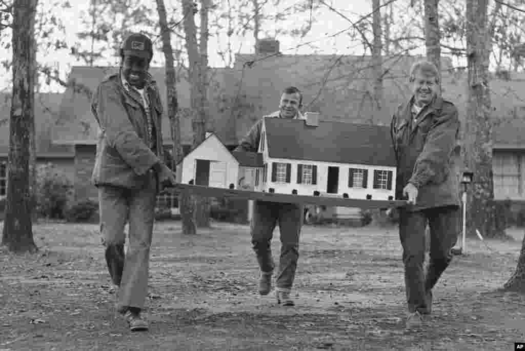 17 января 1977 года. За несколько дней до инаугурации Картер был занят переездом в Белый дом — на этом кадре он переносит кукольный домик своей дочери Эми. Переезжал Картер несколько раз: помимо Белого дома, он также жил в Аннаполисе, в Атланте, служил на Гавайях и в Коннектикуте, но всегда возвращался в свой старый дом в Плейнсе (на заднем фоне).