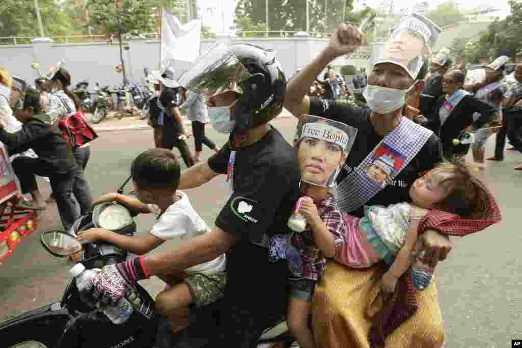 Sebuah keluarga ambil bagian dalam demonstrasi menuntut pembebasan warga di tengah peringatan Hari Perempuan Internasional di Phnom Penh, Kamboja (8/3). Para demonstran memakai topeng Yoam Bopha, seorang warga desa Boeung Kak yang ditahan setelah memprotes penggusuran rumahnya menyusul pembangunan perumahan mewah. (AP/Heng Sinith)