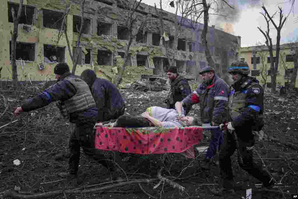 Ukrainian emergency employees and volunteers carry an injured pregnant woman from a maternity hospital severely damaged by Russian shelling in Mariupol.