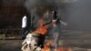 A protester, who is against President Pierre Nkurunziza's decision to run for a third term, gestures in front of a burning barricade in Bujumbura, Burundi, May 14, 2015. 