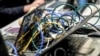 FILE - Wires are plugged into laptop computers as people work during the 11th International Cybersecurity Forum, Jan. 22, 2019.