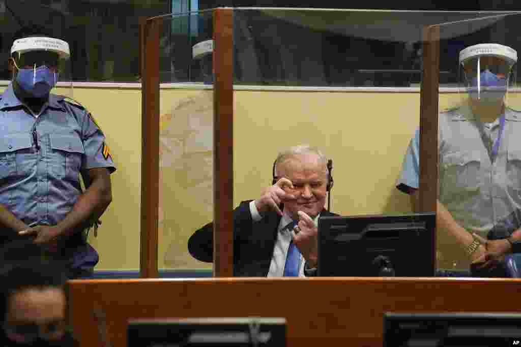 Former Bosnian Serb military chief Ratko Mladic imitates taking pictures as he sits the courtroom in The Hague, Netherlands, where the U.N. court delivers its verdict in the appeal of Mladic against his convictions for genocide and other crimes in the Bos