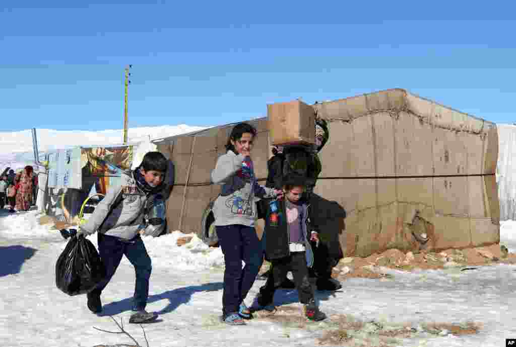 Para pengungsi Suriah membawa barang bantuan dari pemerintah setempat di kota Romawi kuno Baalbek di Lebanon timur (15/12). (AP /Bilal Hussein)