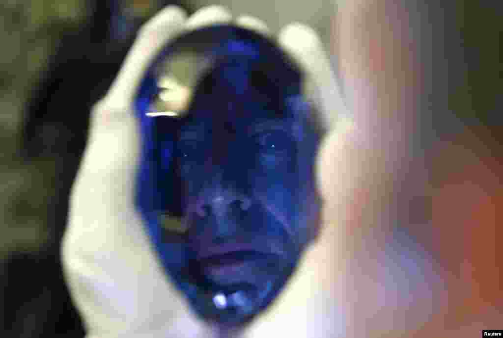 Philanthropist Maurice Ostro is reflected in his Ostro stone, the largest known blue topaz stone, as he holds it for media at the Natural History Museum in London, Britain.